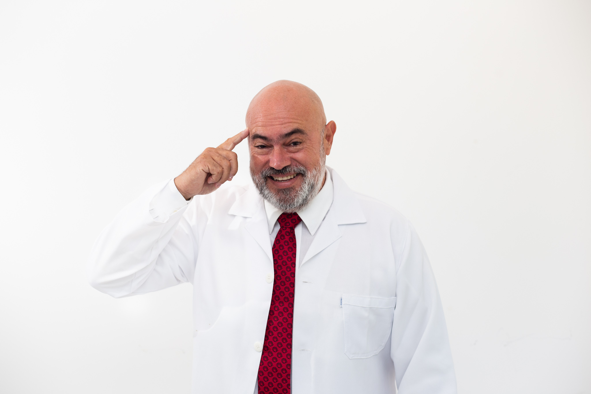 Dr. Jô Furlan sorrindo e apontando para a cabeça